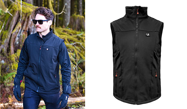 Man in a black heated vest standing in the forest.