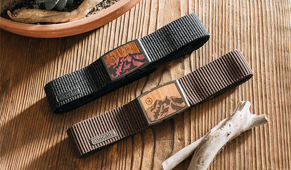 Two stretchy belts with a wooden buckle displayed on a wooden table.